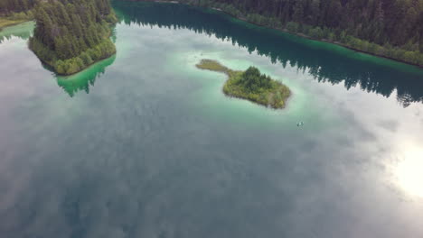clear turquoise mirror lake and a lonely fishing boat beside an island in the morning