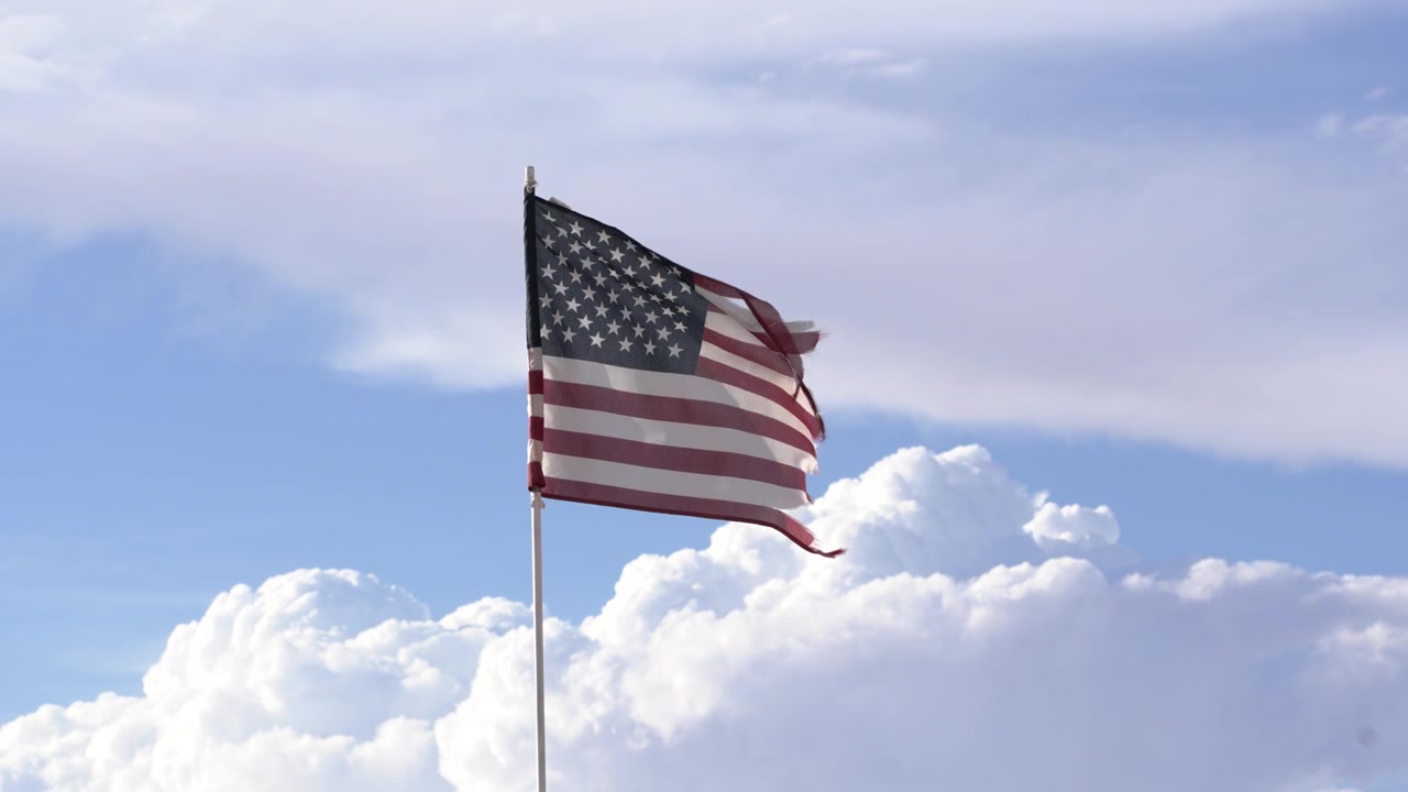 Amerikansk flag vajende i vinden mod en skyet baggrund i slowmotion i 4K