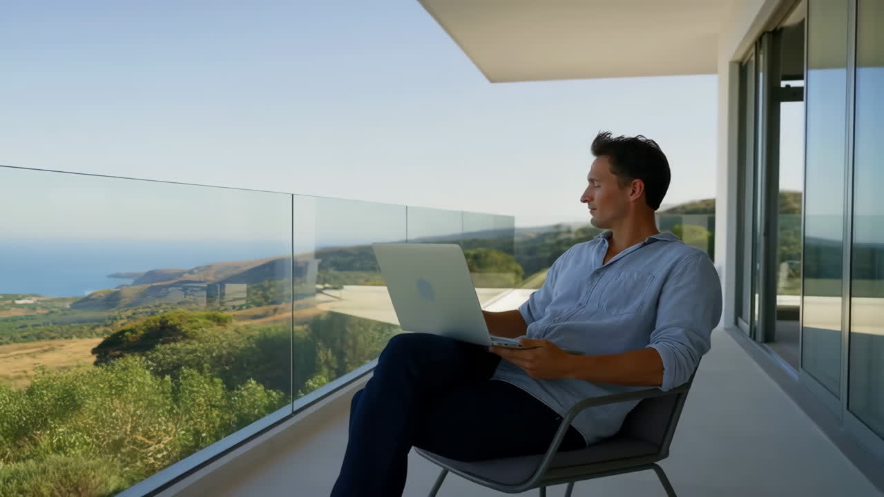 Man working on laptop on a balcony with a view