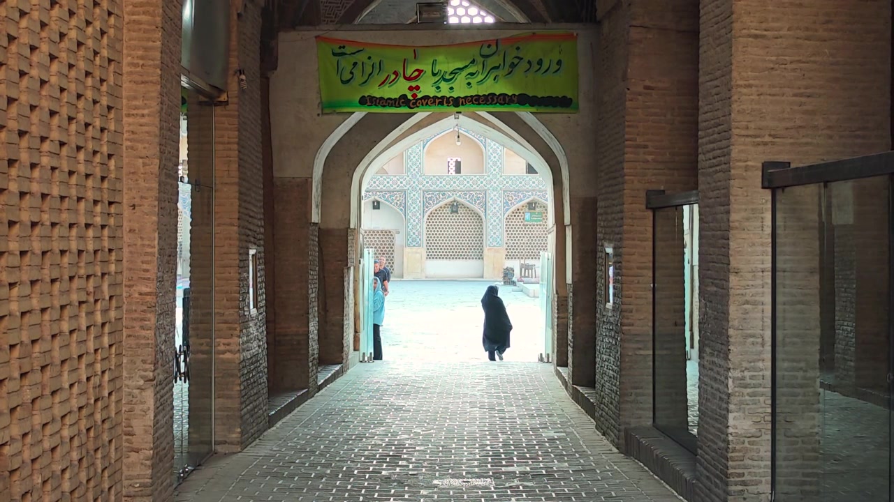 Người phụ nữ mặc Chador đi qua kiến trúc truyền thống Iran