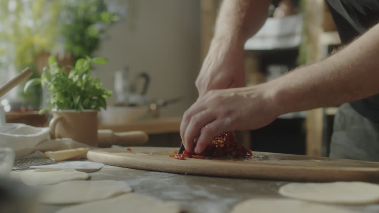 Person Chopping Ingredients on a Cutting Board in a Kitchen