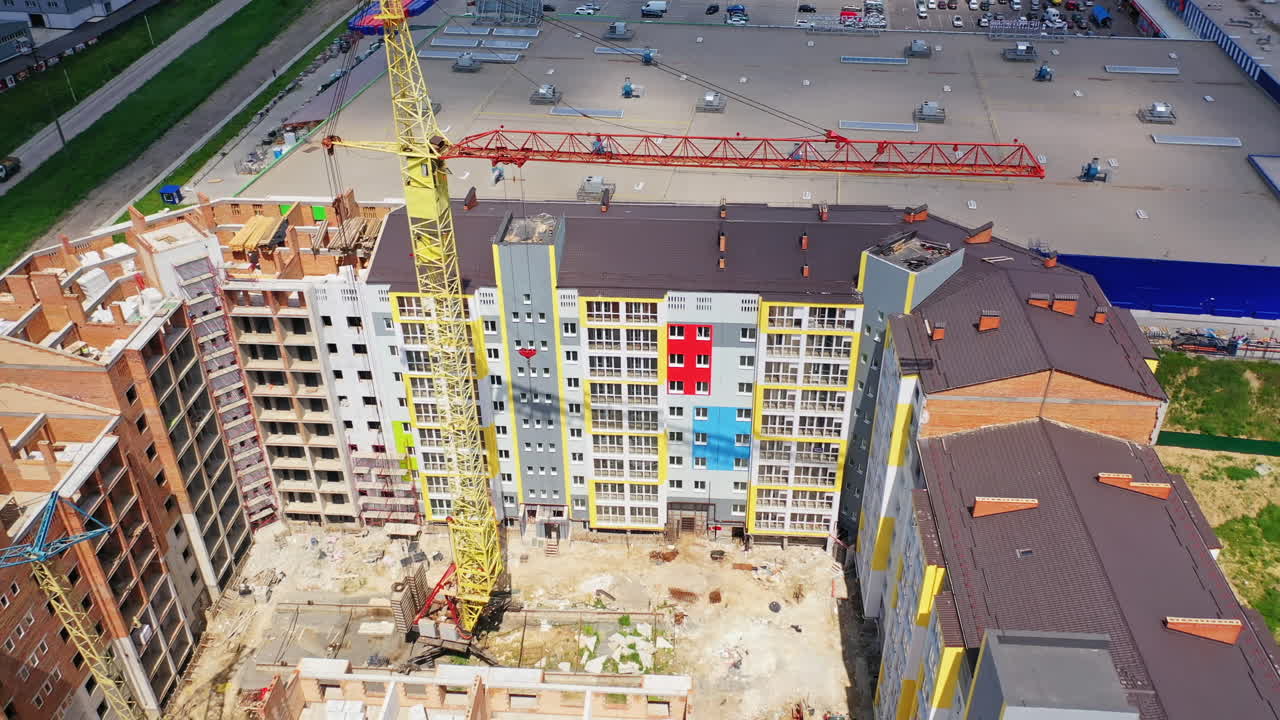 Construction of a multi-storey apartment building. Building of a multi-quarter houses in the city. Tower crane on a construction site. Aerial view.