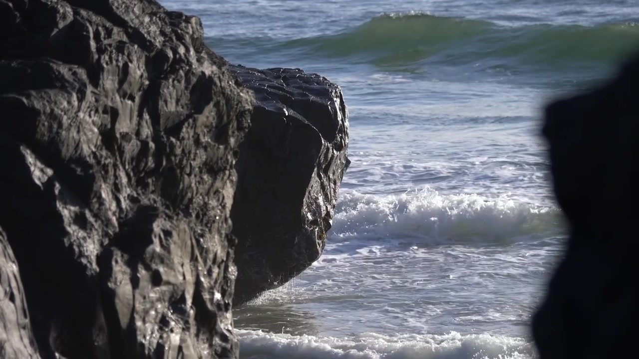 Havbølger bruser ind og slår mod klipperne på stranden. Statisk.