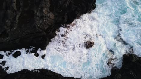 Imágenes-De-Drones-Estables-De-Arriba-Hacia-Abajo-De-Olas-Corriendo-Entre-Rocas-De-Lava-Enfriadas