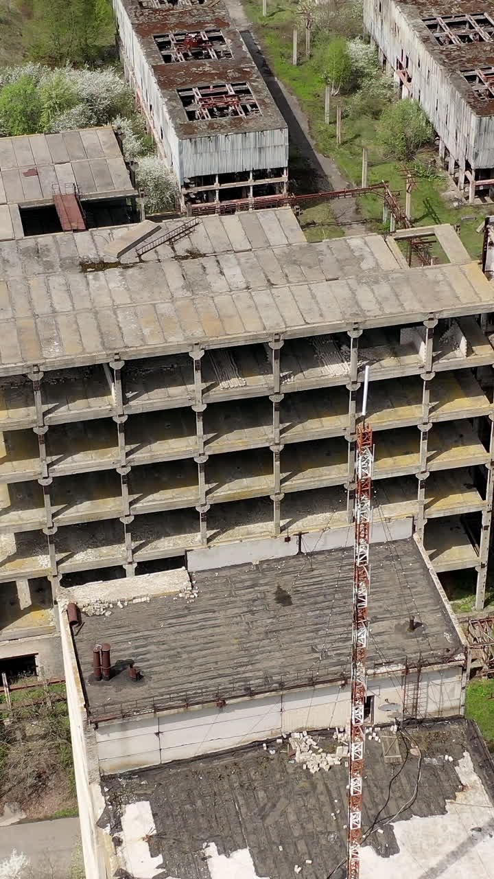 Old industrial edifices. Ancient manufactory with ruined buildings in abandoned zone in springtime. Camera rising up. Vertical video