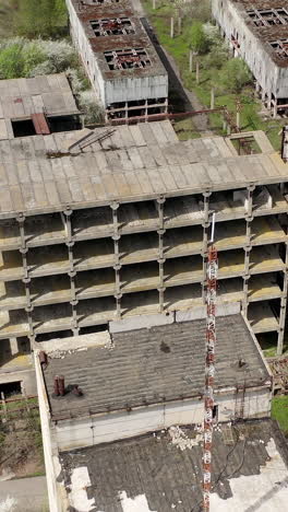 old industrial edifices. ancient manufactory with ruined buildings in abandoned zone in springtime. camera rising up. vertical video