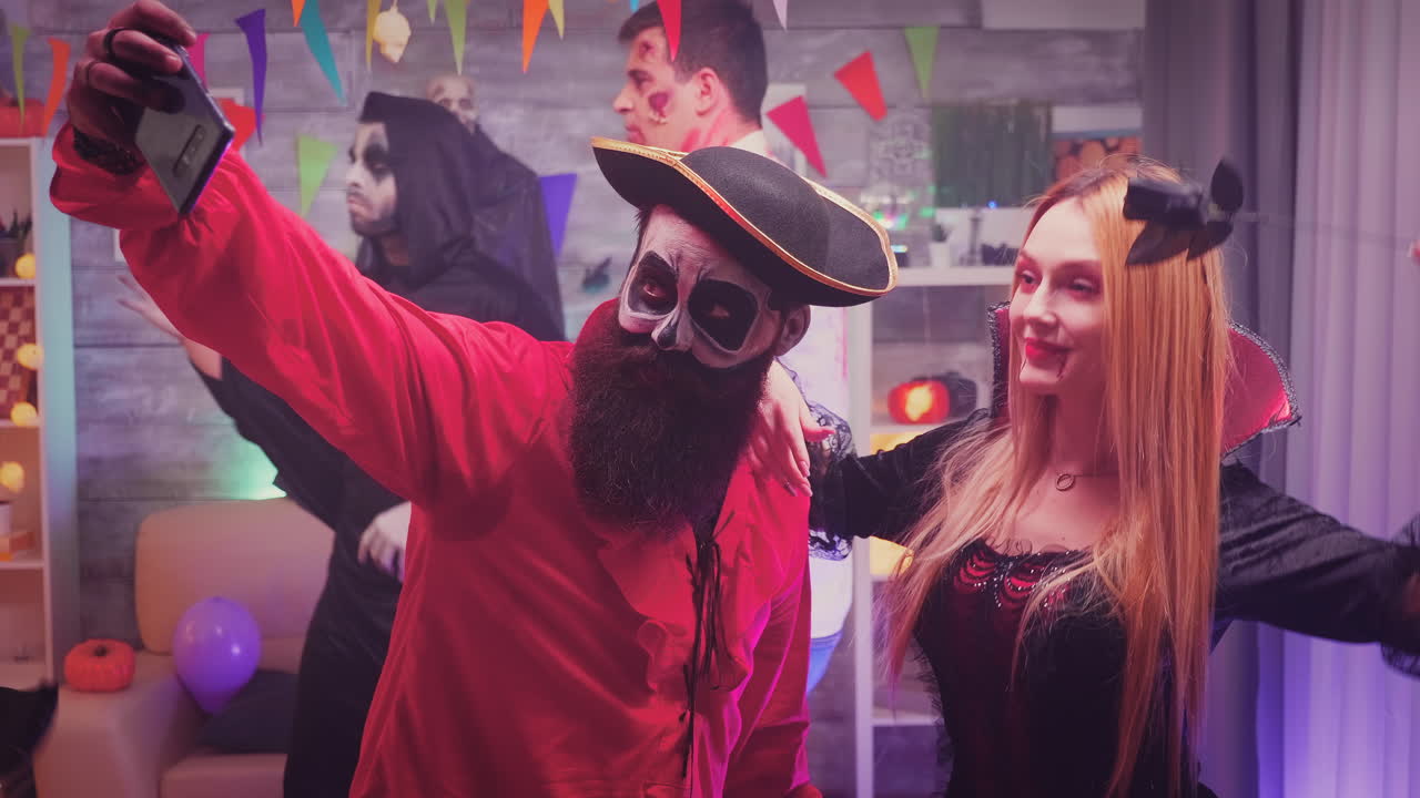 personajes de piratas espeluznantes y brujas sangrientas tomando una selfie en una fiesta de halloween