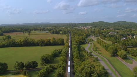 cargo train running at the drone filming from overhead in tennessee with a lot of green trees and foliage around