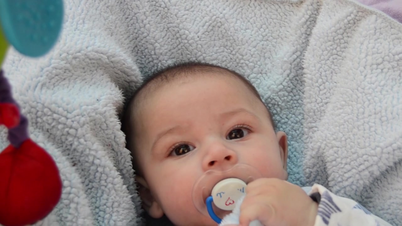 cute tree months old baby boy in the bouncer rotating