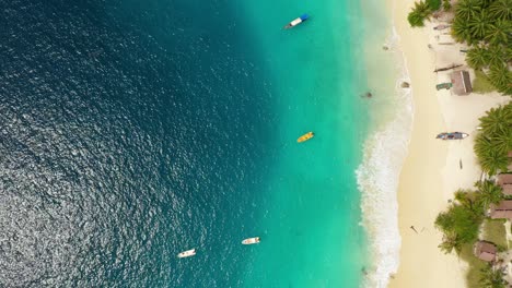 Aerial-view-of-turquoise-tropical-water-with-boats-and-huts-on-beach-at-Asu-Island,-North-Sumatra,-Indonesia