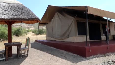 Establisher-shot-of-sun-umbrella-and-chairs-by-tented-accommodation,-Tanzania