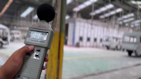 hand of people is holding sound level meter to measuring the noise of industrial production room