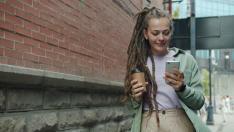 woman walking in city with coffee and phone