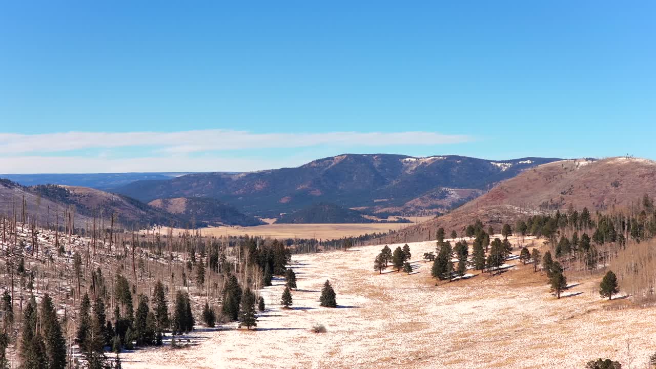 Professionellt drönarfilmmaterial visar en filmisk glidande bana över en snöig bergstopp med utsikt över en stor alp caldera. Fångar vidden av vildmarken och skogen. Perfekt för reseannonser.