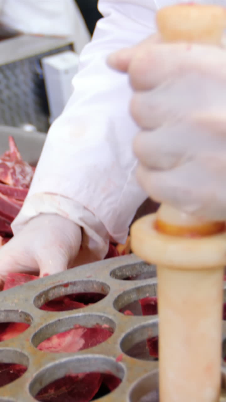 Butcher putting meat into mincer machine