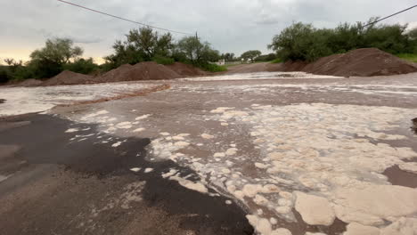 foamy brown water from flash flood in arizona rural street, panning