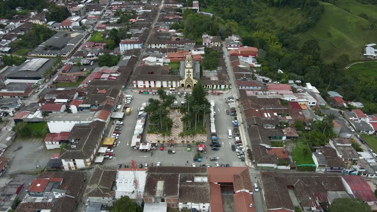 Panoramic aerial pullback from Salento Colombia square with chapel at center of valley