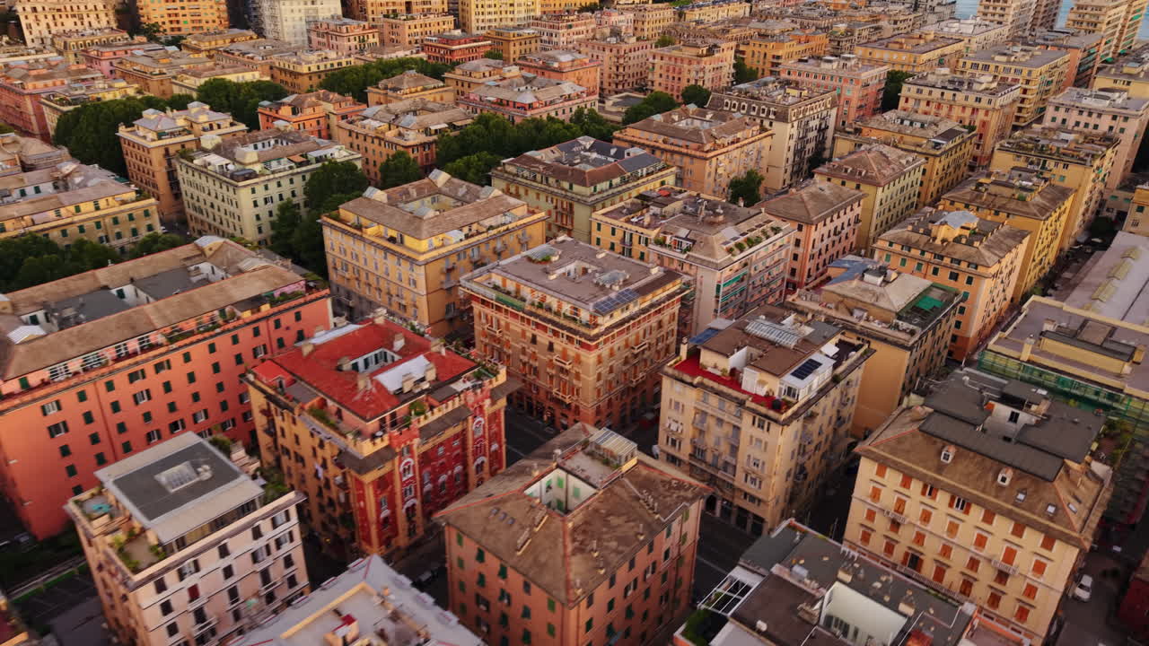 Drone descending shot over rooftops of colorful buildings in Genoa, Italy, at sunset