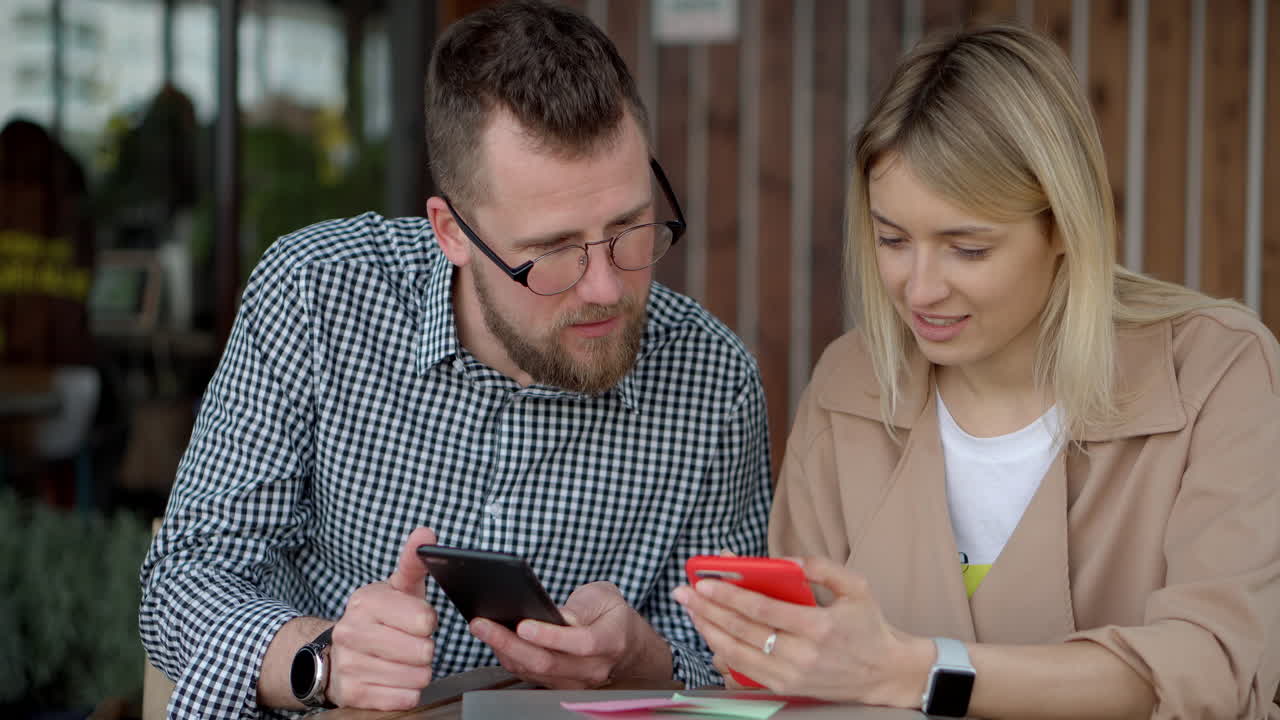 pareja mirando teléfonos inteligentes en un café