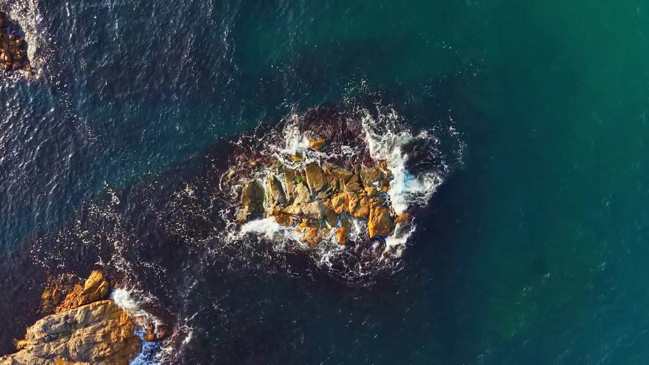 View of a rocky island surrounded by ocean waves during daytime