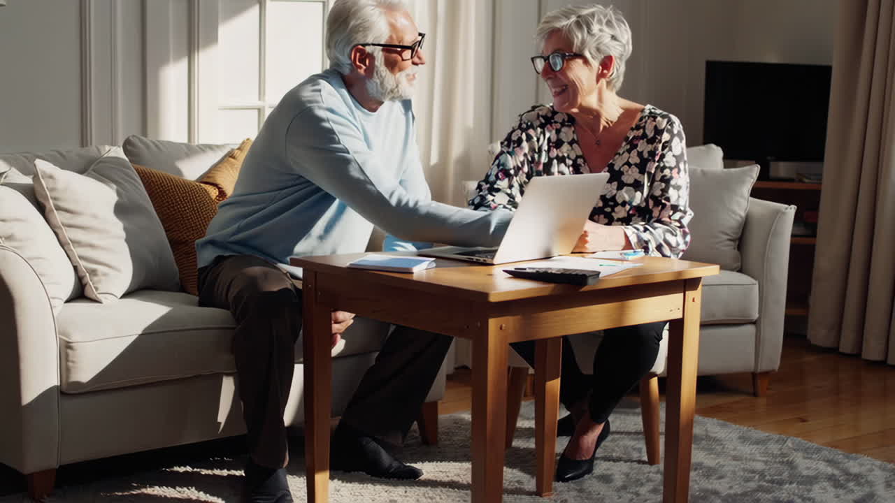 An elderly couple managing their finances at home with a laptop