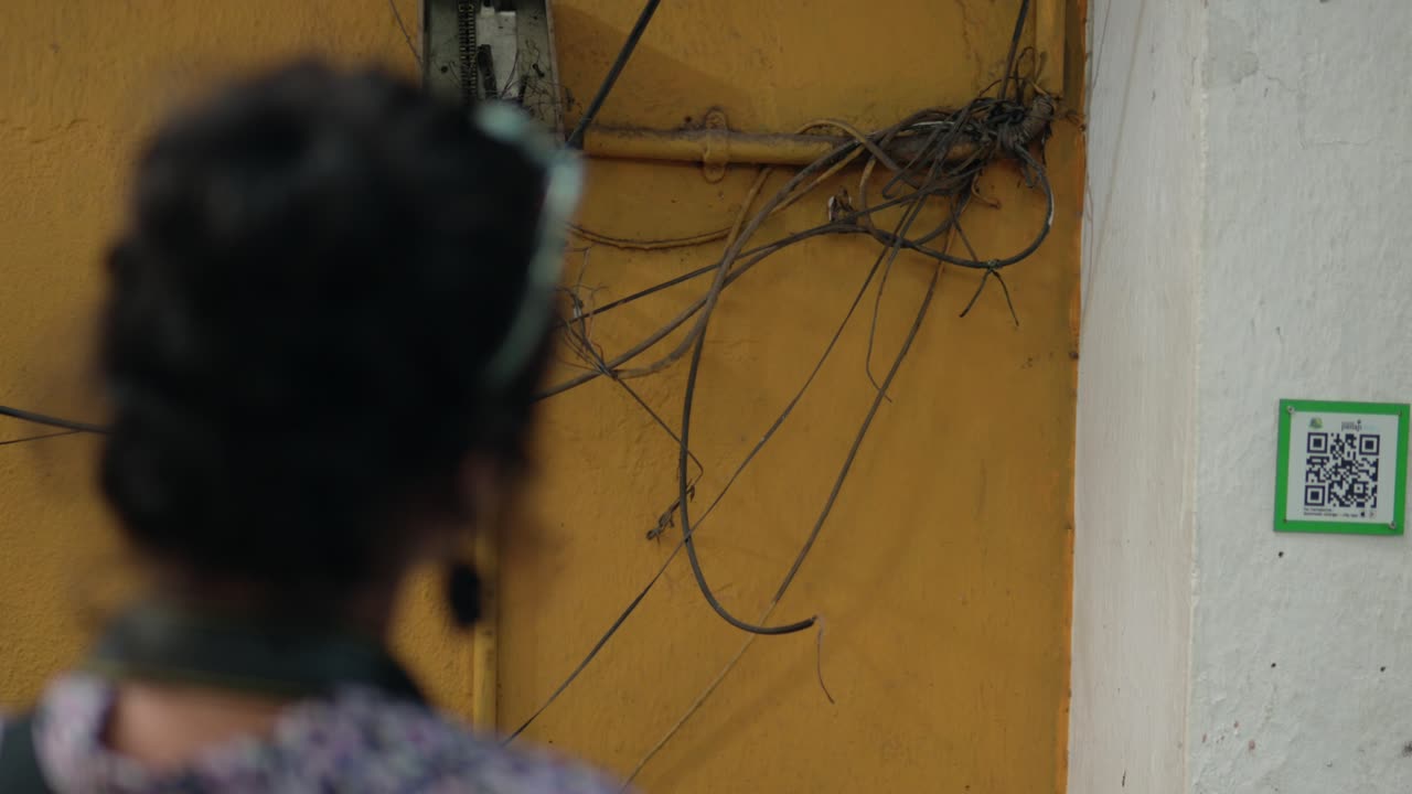 un primer plano de una chica desde la parte de atrás tomando fotos de la pared