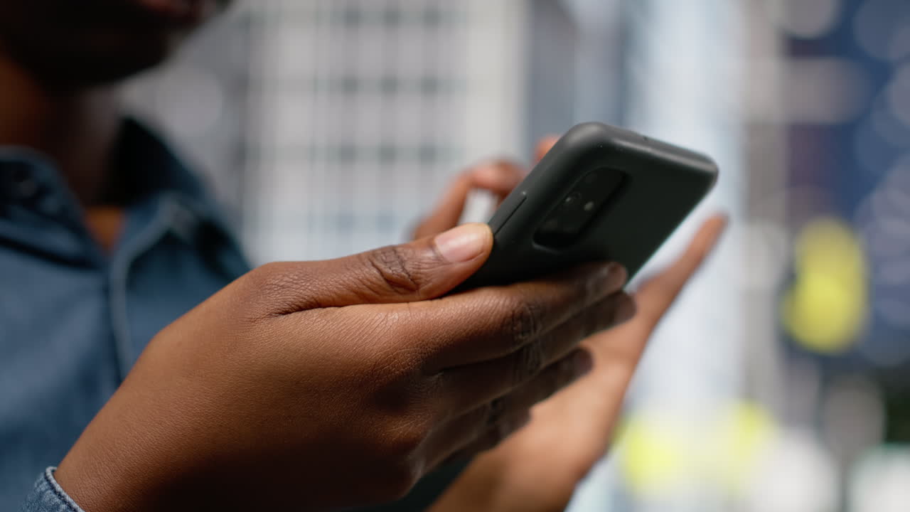 Nærbillede af kvinde, der surfer på nettet på sin mobiltelefon, mens hun går på en bygade.