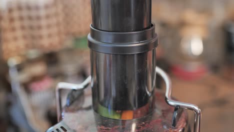 female hand presses fresh produce into juicer