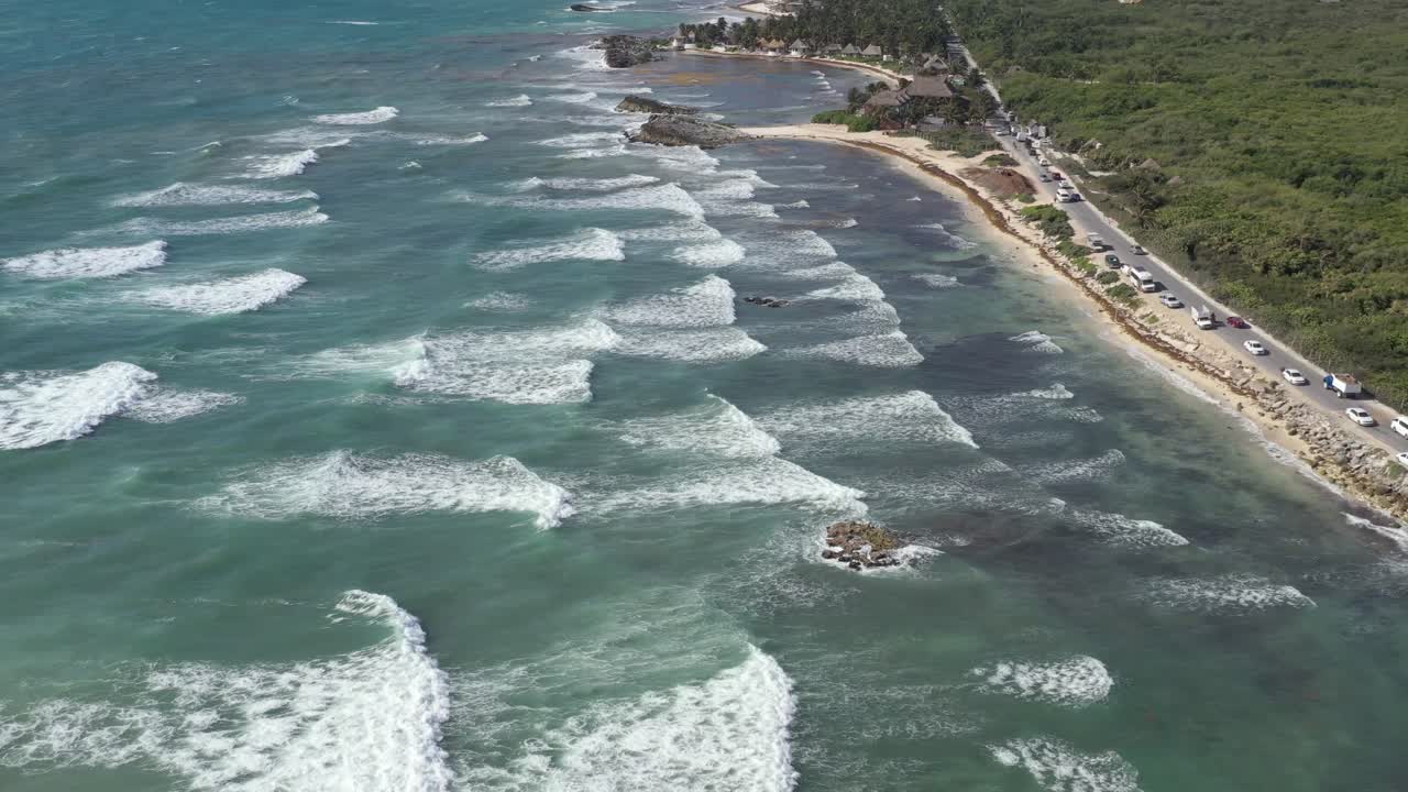 toma aérea de drones de olas gigantes que llegan a la playa de arena de riviera maya en tulum - autos conduciendo en la carretera de la costa - arrecife de coral en agua transparente del mar caribe