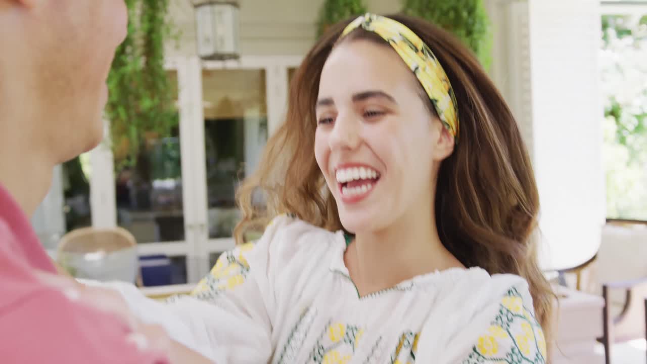 una feliz pareja biracial pasando el tiempo en casa tomados de la mano y bailando