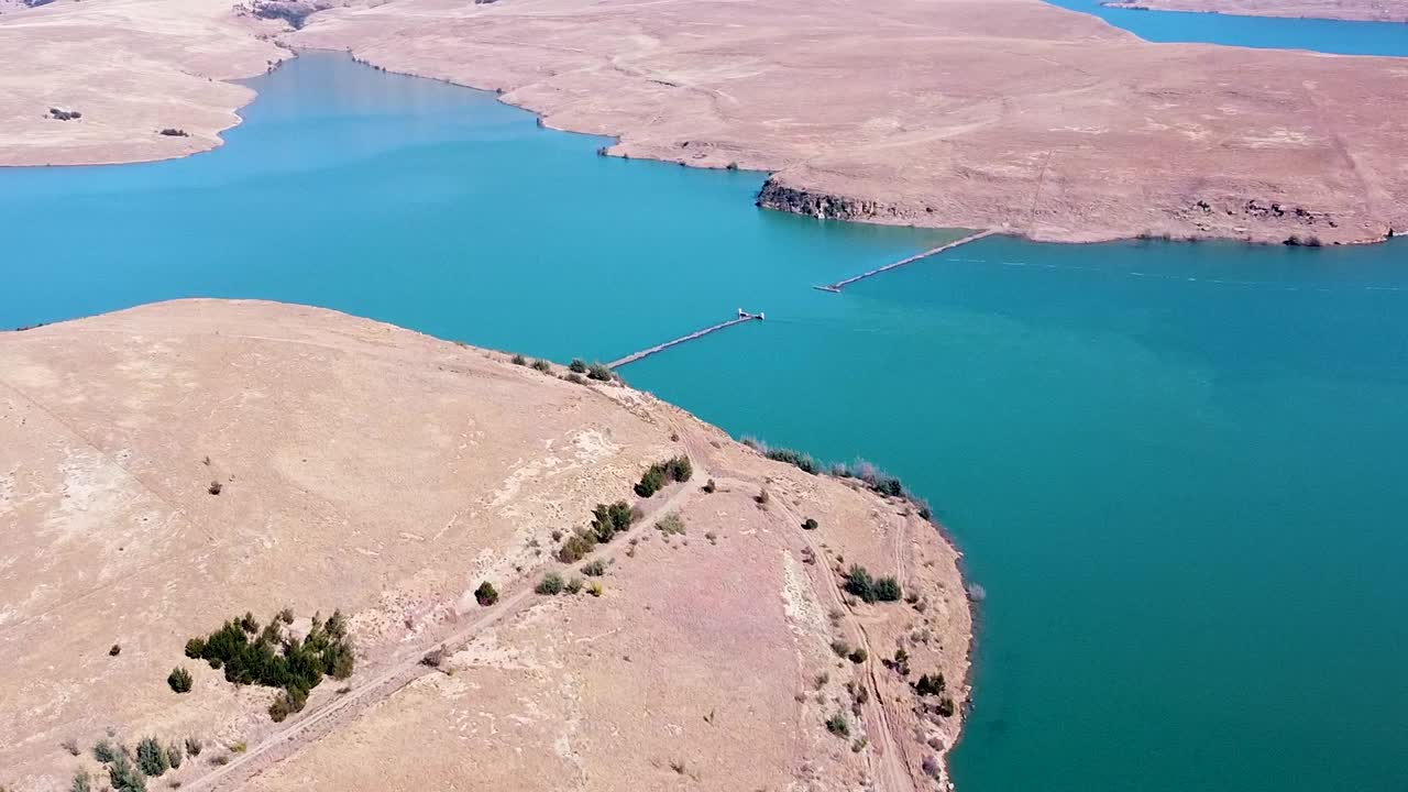 Aerial drone shot of the beautiful blue waters of the Driefkloof Dam, the surrounding veld landscape is dry, dusty and lifeless, Free State, South Africa