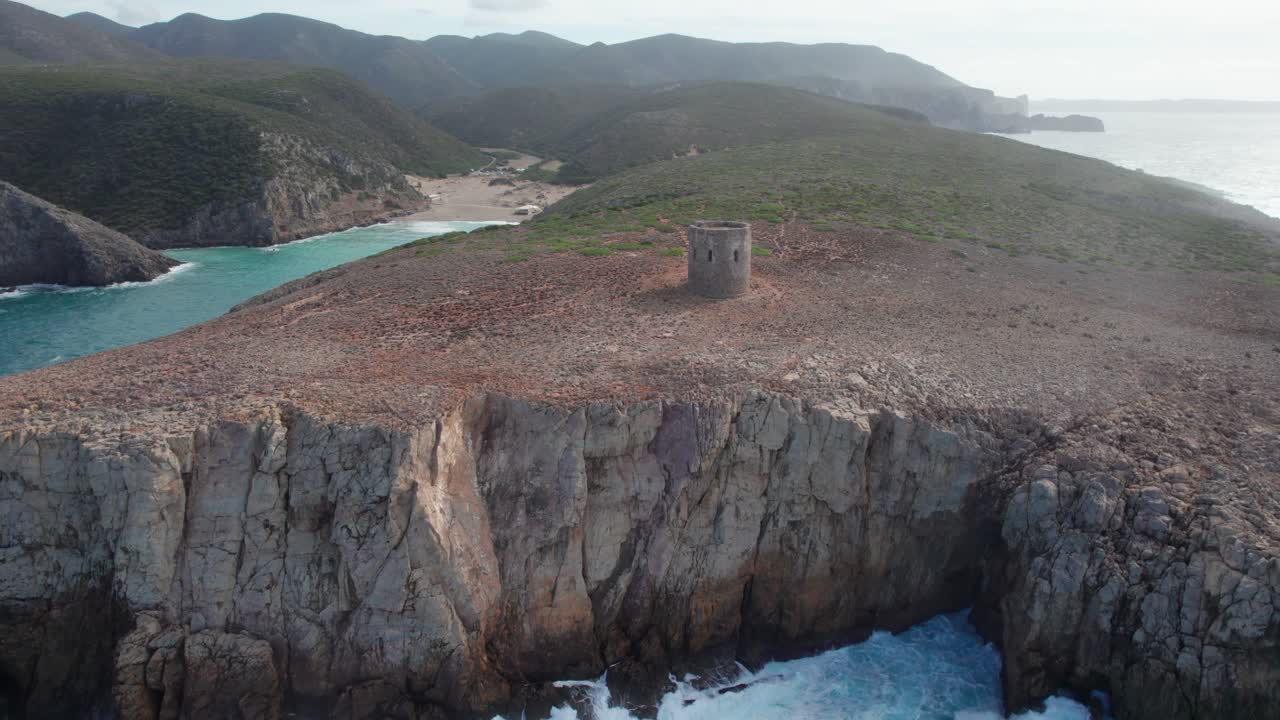 Vista aerea con drone della storica Torre di Cala Domestica su una scogliera con onde che si infrangono sotto