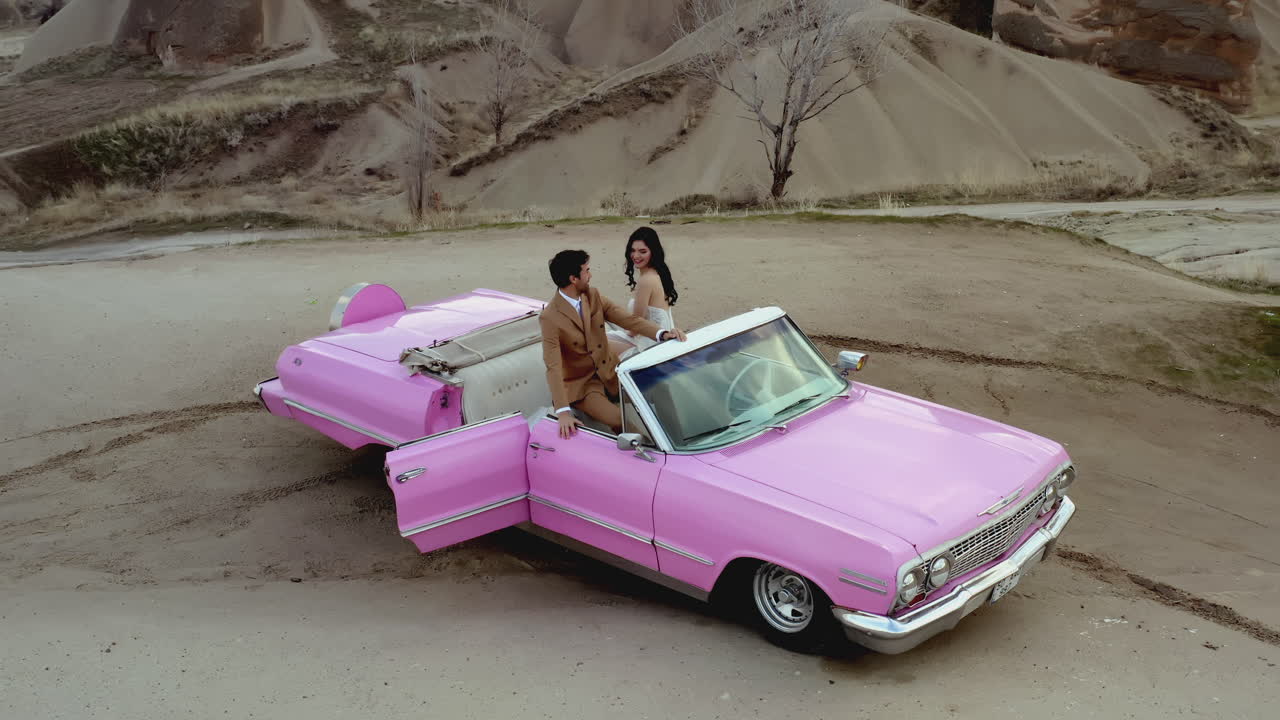 Romantisches Paar in einem rosafarbenen Vintage-Cabrio