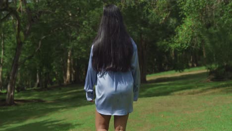 a young east indian girl walking at the park in a blue shirt on a suuny day