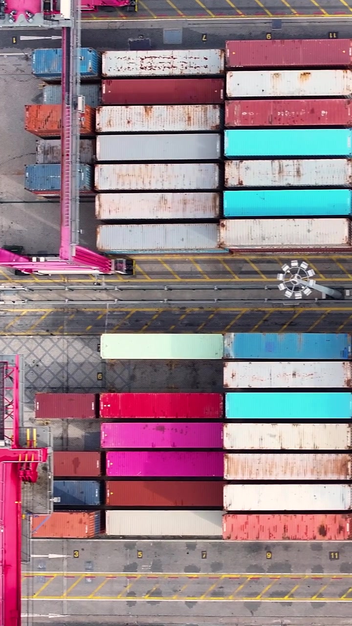 The container terminal shows various shipping containers arranged orderly. Cranes lift cargo onto a container ship. This highlights global shipping and international trade activities.