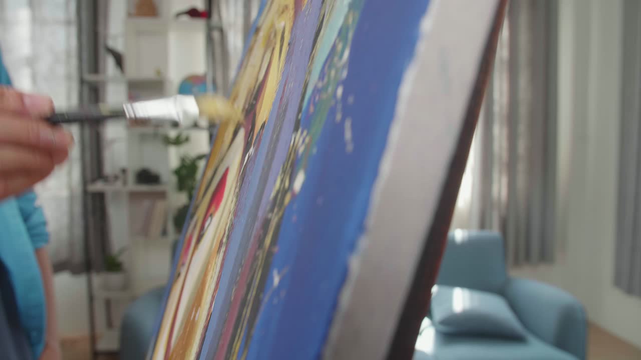 cerca de una mano sosteniendo un pincel de colores mixtos y pintando el rostro de una niña en el lienzo