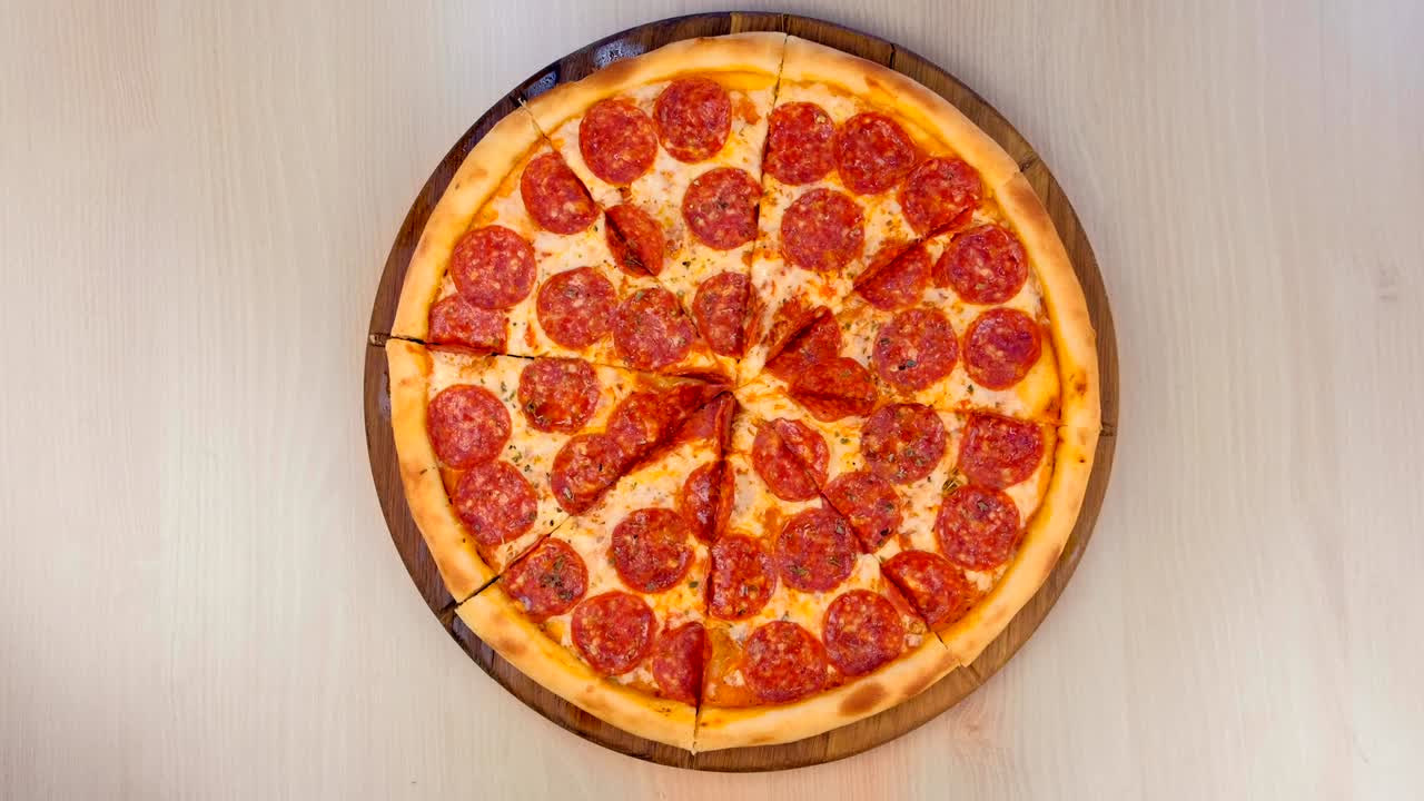 Affettare pizza al salame su tagliere di legno sul tavolo