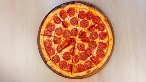 cortando pizza de salami en una tabla de madera en la mesa.