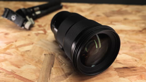 close up of camera lens with tripod on wooden table