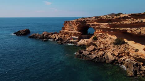 Aerial-Flying-Towards-Secret-Cave-Hole-On-Cliff-Edge-At-Sa-Figuera-Borda