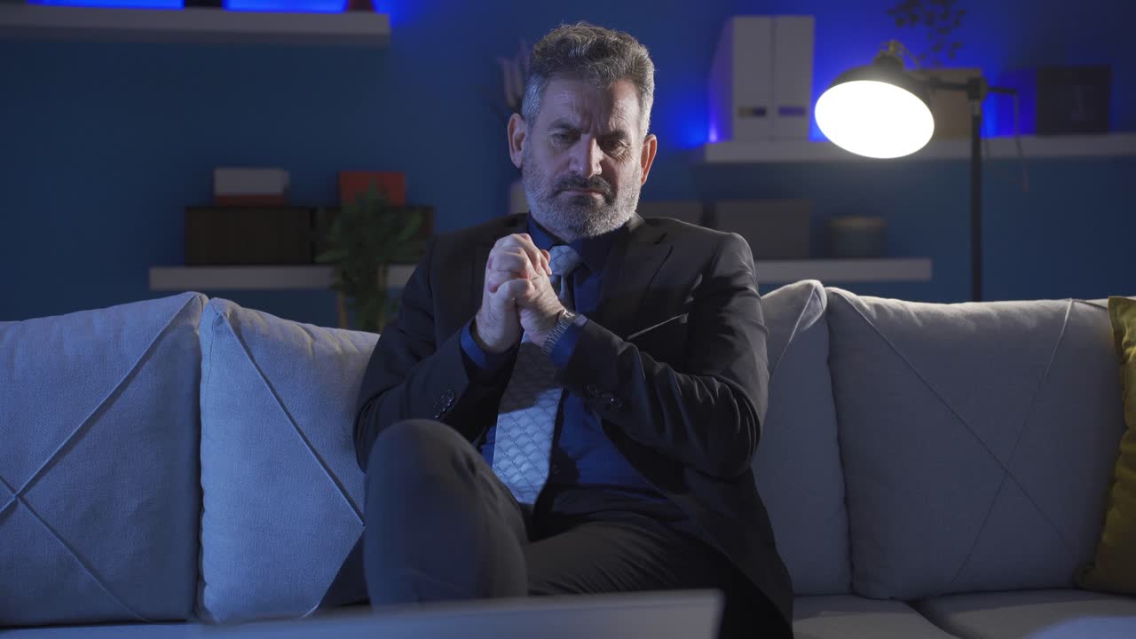 hombre de negocios maduro trabajando por la noche en casa mirando la computadora portátil estresado y reflexivo.