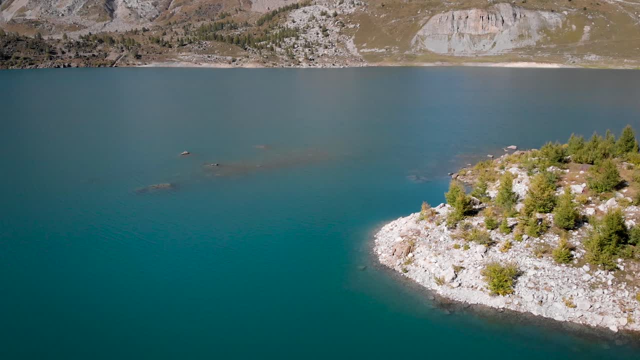 воздушный перелет над островами в водах озера саланф в вале, швейцария в солнечный осенний день в швейцарских альпах с обширным видом на окружающие альпийские вершины и скалы
