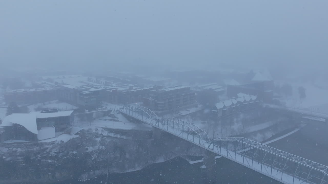 Aerial footage during a snowstorm that rotates over the Walnut Street Walking Bridge in Chattanooga, Tennessee.