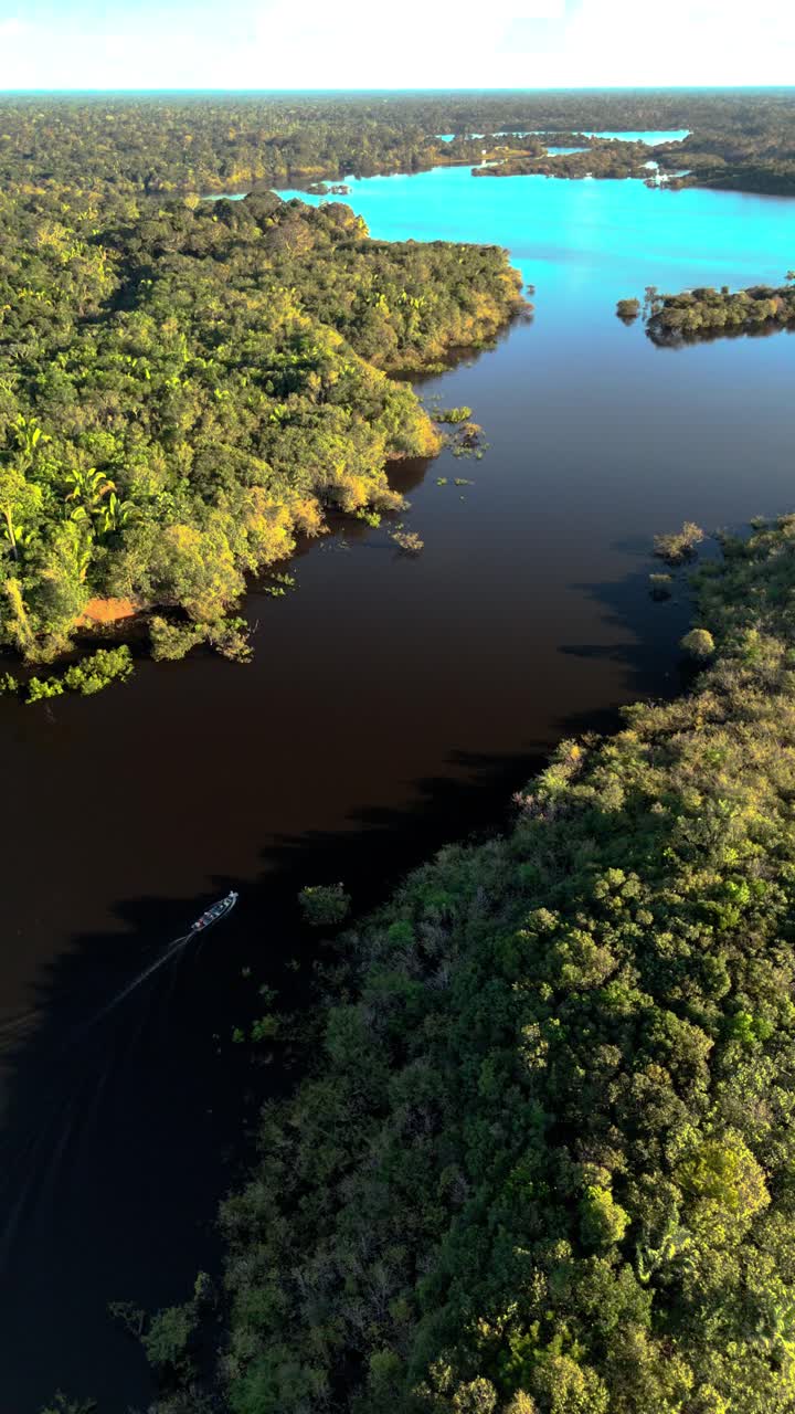 Vertical: Drone orbits boat on Amazon River with vast green jungle horizon of the Amazon Jungle, Brazil