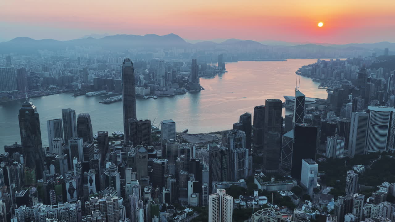 Cinematic aerial view of Hong Kong skyline shrouded in mist at blue hour, with glowing skyscrapers and Victoria Harbour fading into a moody, atmospheric twilight