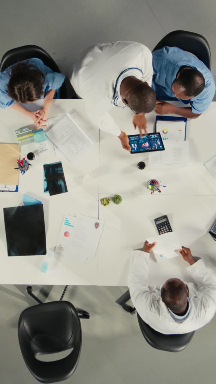 Vertical Video Top down view of diverse physicians team reviewing clinical records
