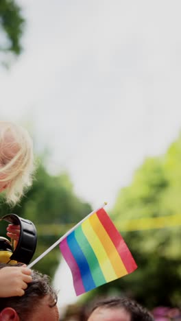 child holding rainbow flag at pride parade