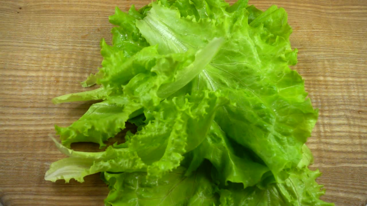 Foglie di lattuga cadono su una tavola. Rallentatore.