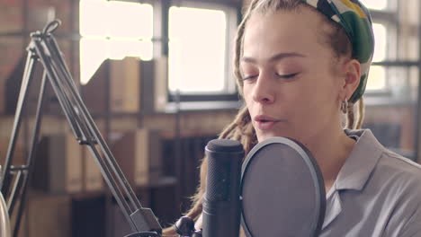 close up view of woman with dreadlocks talking into a microphone recording a podcast 1