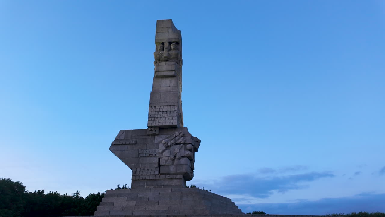 Detailed, low-angle shot of the granite Monument to the Defenders of the Coast at Westerplatte against a fading blue evening sky